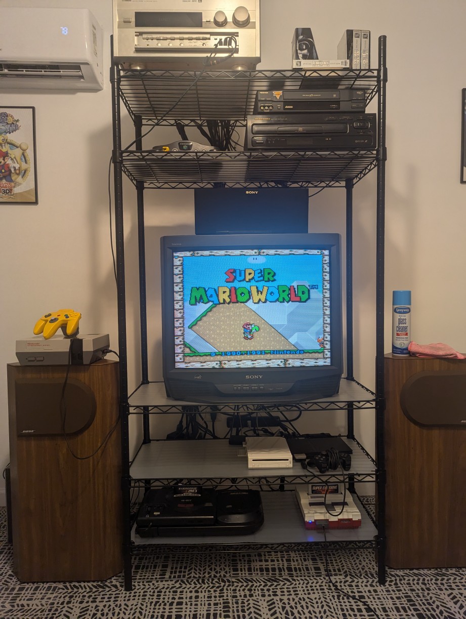 A vintage CRT on a stand with retro game systems hooked up, playing Super Mario World on SNES